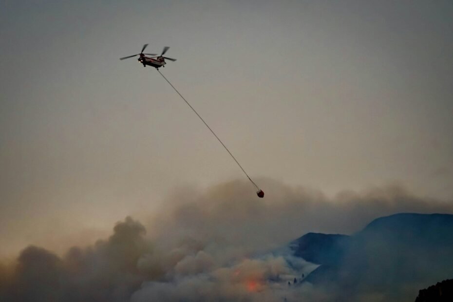 a helicopter flying through the air with a hose attached to it