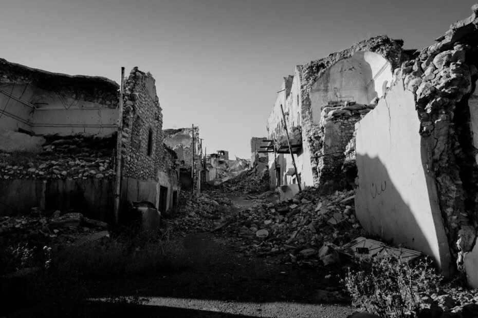 A narrow street in Sinjar lined with ruined stone buildings and piles of rubble